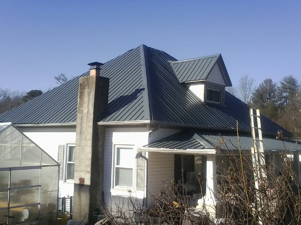 Dark blue standing seam metal roof on a white farmhouse with dormer — Slate & Tile Roof Repair by Roofing Brothers in Willow Wood