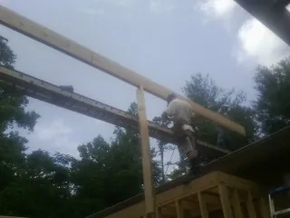 Carpenter setting a ridge beam over a new addition frame — Ice Dam Removal by Roofing Brothers in Willow Wood
