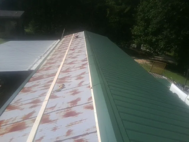 Old rusted panels beside newly installed green metal roofing — Wind Damage Roof Repair by Roofing Brothers in Willow Wood