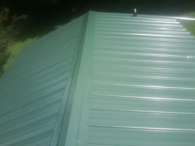 New green metal panels meeting at the ridge of a roof — Flat Roof Repair work by our crew in Willow Wood