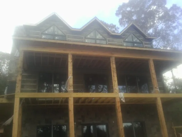 Dormers and porch framing on a large log home under construction — Roof Coating work by our crew in Willow Wood