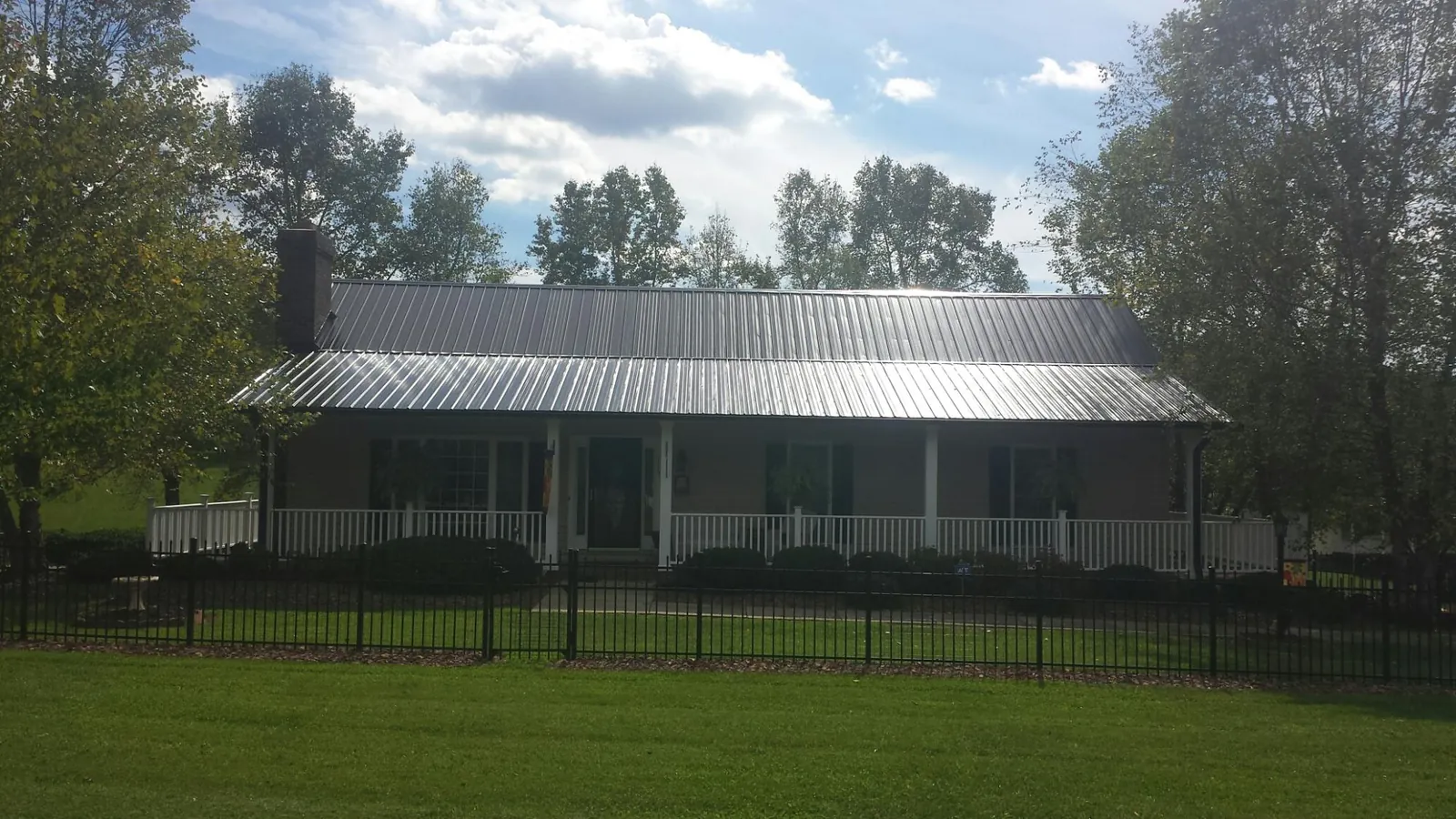 Gray metal roof on a brick ranch with a full width front porch — Gutter Guard Installation work by our crew in Willow Wood