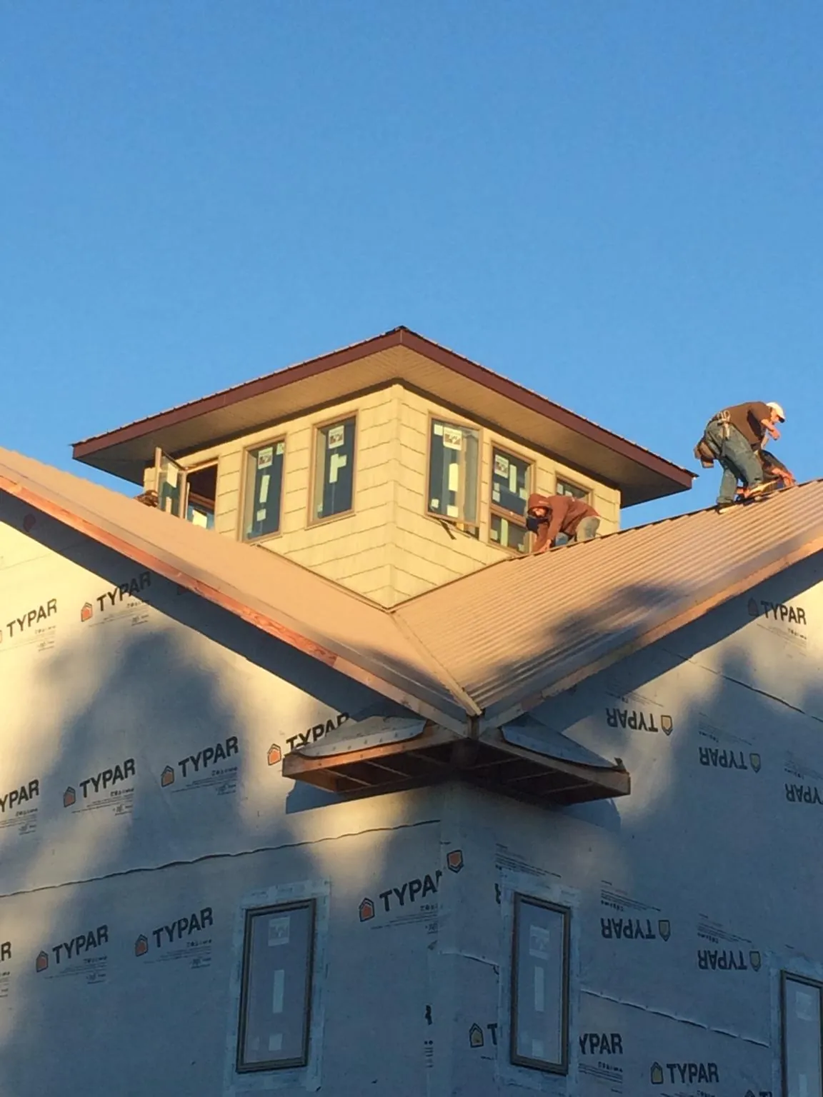 Roofers working around a rooftop cupola on a new metal roof at sunset — Roof Waterproofing in Willow Wood by Roofing Brothers